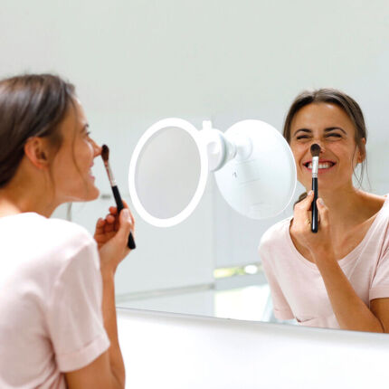 Frau schminkt sich vor einem Spiegel